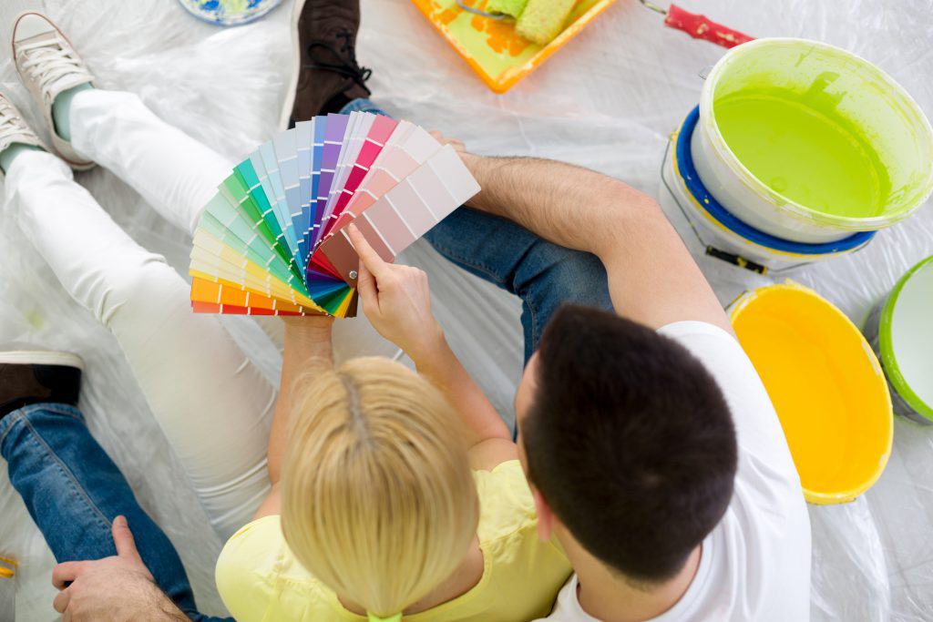 Couple sitting on floor and choosing color for painting, top view